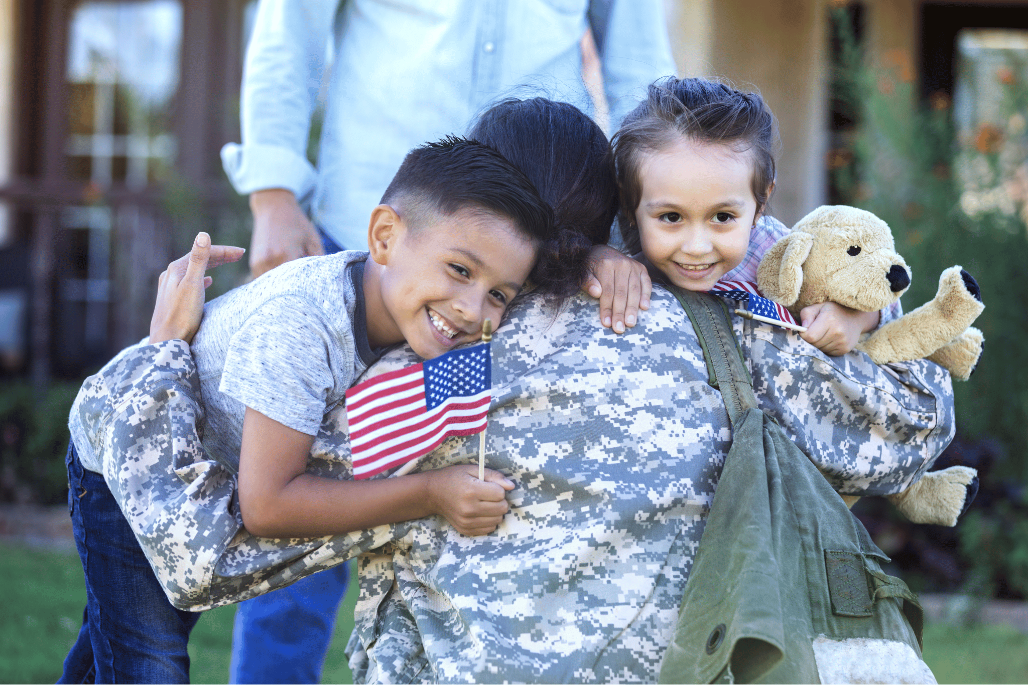 Military children embracing service member with American flags
