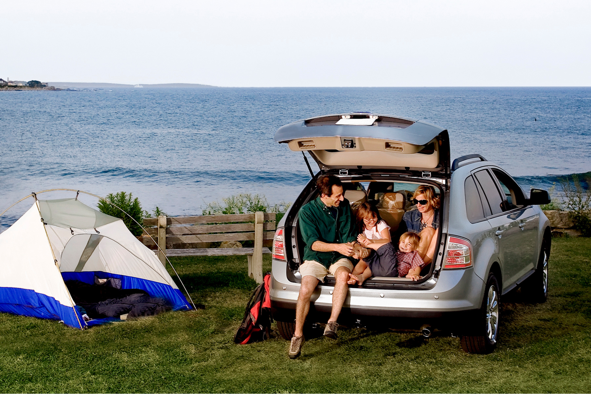 Happy family enjoying their safe used SUV on a coastal camping trip